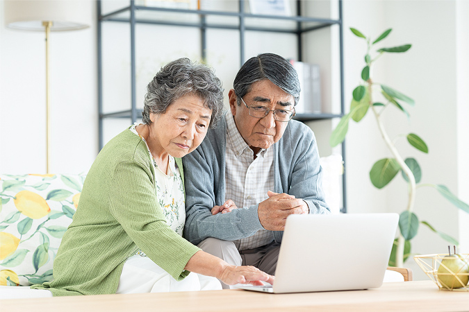 パソコンで調べ物をしている夫婦のイメージ画像